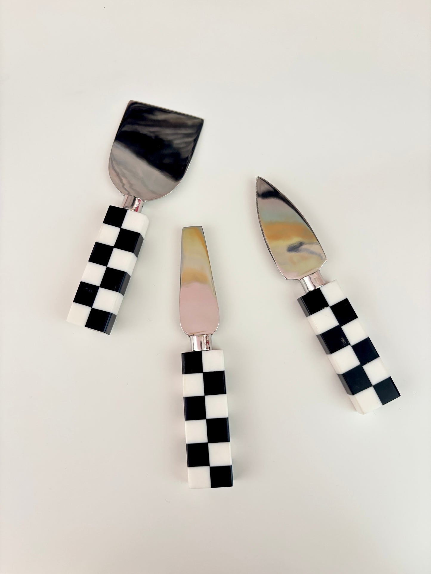 Three cheese knives with checkered handles on a light gray background