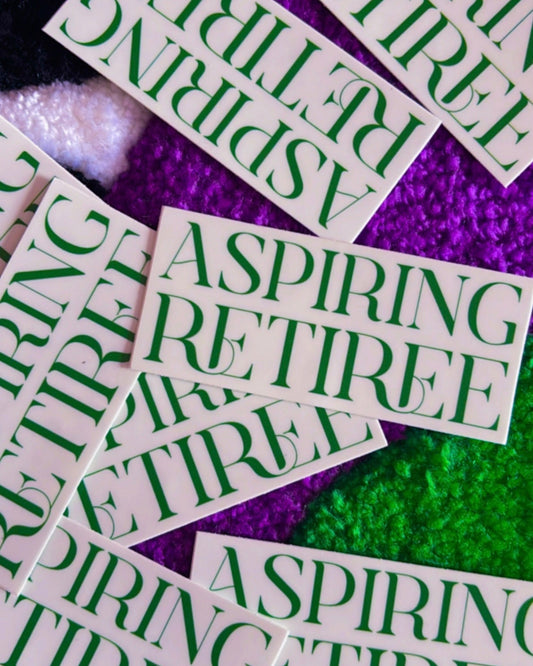 Multiple 'Aspiring Retiree' stickers on a glittery purple and green background