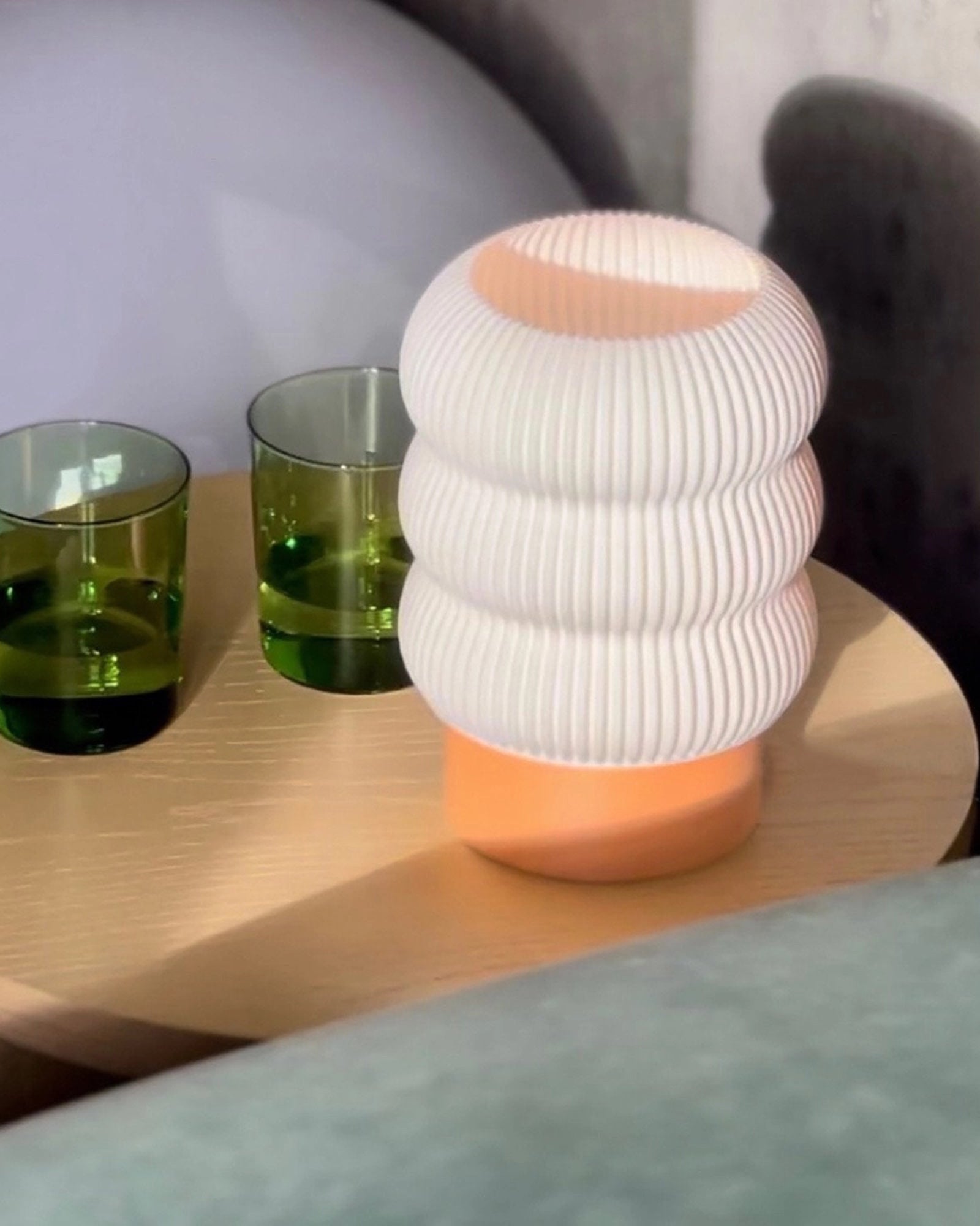 Pleated table lamp in warm peach Nectar color with matte finish styled on a wood table